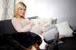 Healthy pregnant woman lying on a couch with her dog.
